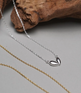 Detail of 925 sterling silver heart pendant necklace on a natural wood aesthetic background