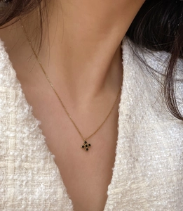 Detail shot of a black zircon clover pendant necklace worn by a female model