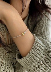 Close-up of a minimalist dual-tone gold and silver beaded necklace on model neck