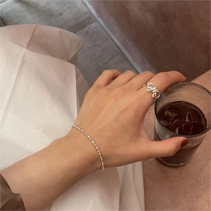 Gros plan sur une bague nœud minimaliste en argent S925 et un bracelet en perles fines