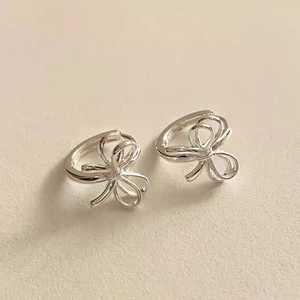 Détail macro de boucles d'oreilles nœud papillon en argent 925 avec finition polie