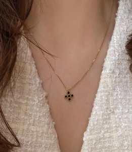 Close-up of golden necklace with black zircon clover pendant worn on female model neck