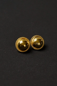 Detail of gold dome stud earrings with retro rope twist border on black textured surface