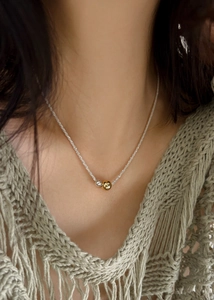 Close-up of a delicate shimmer chain necklace with gold and silver bead pendants