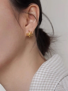 Gros plan de boucles d'oreilles nœud doré portées par un mannequin avec élégance