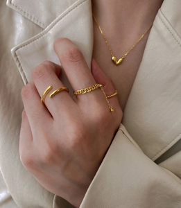 Close-up of a 925 silver gold-plated heart pendant and trendy minimalist rings on model