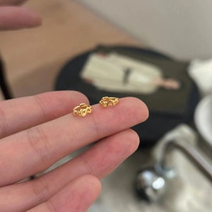 Mini créoles en argent sterling 925 doré en forme de S présentées à la main levée