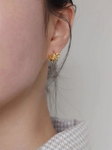 Gros plan de boucles d'oreilles papillon dorées élégantes portées avec un style épuré