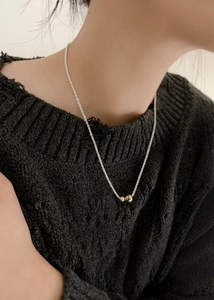 Close-up of a minimalist necklace featuring two-tone gold and silver beads on a model