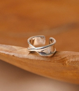 Macro shot of minimalist polished silver irregular folded ring on warm wood texture