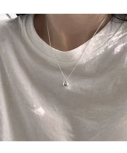 Close-up of a silver teardrop pendant necklace worn on neck with a simple white T-shirt