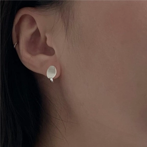 Gros plan de boucles d'oreilles ovales minimalistes en argent 925 portées avec fini poli