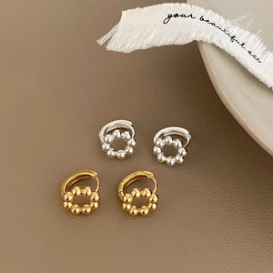 Detailed view of gold and silver beaded hoop earrings on a dark leather surface