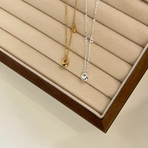 Detailed shot of silver and gold bean pendants on delicate chains in a display box