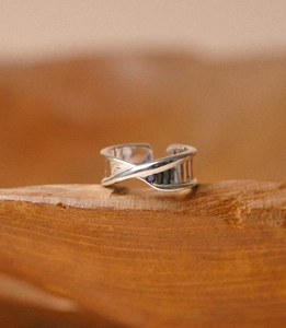 Macro shot of minimalist silver 925 adjustable ring on a rustic wooden stand