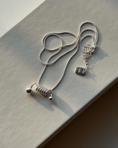 Macro view of S925 sterling silver spiral spring pendant on a fine snake chain necklace