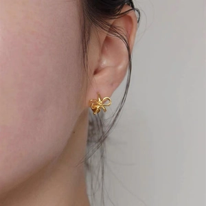 Élégantes boucles d'oreilles nœud en argent 925 doré portées pour un style minimaliste