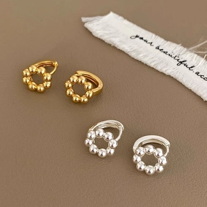 Detail of minimalist beaded hoop earrings in gold and silver finish on textured background