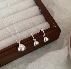 Detailed view of silver solid bean pendant necklace and matching hoop earrings set