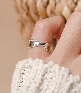 Macro shot of 925 sterling silver irregular twisted ring on finger with soft knit background