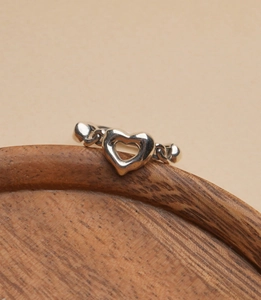 Close-up of S925 sterling silver heart ring with textured chain band on wooden tray