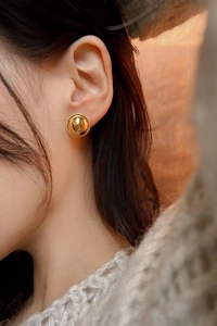 Close-up of vintage gold dome stud earring with rope border on a female model