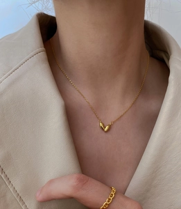 Close-up of a 925 silver heart pendant necklace and gold anchor chain ring on a model