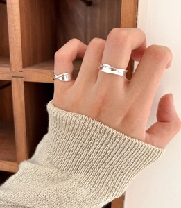 Detailed view of 925 sterling silver stacked rings with irregular wave and crossover designs