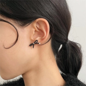 Detail of elegant black beaded bow stud earrings showing intricate texture and silver hardware