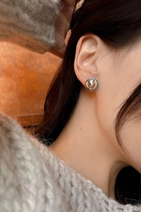 Close-up of minimalist silver dome earrings with twisted rope border on model