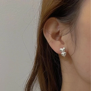 Polished S925 sterling silver double heart stud earrings on model's ear earlobe