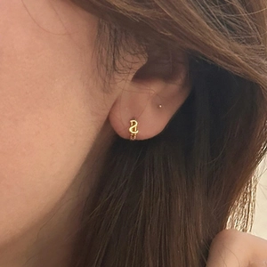 Boucles d'oreilles créoles dorées 18K avec pendentif lettre D portées par mannequin