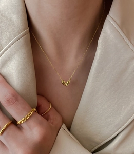 Detail of 925 silver heart necklace in gold and matching rings on a warm leather coat
