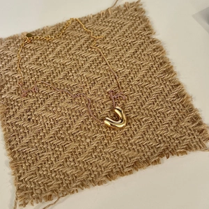 Detailed view of 925 sterling silver V-shape gold necklace on textured brown fabric background