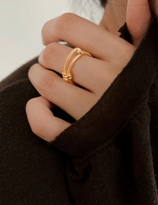 Close-up of golden double-layer knotted ring on model with knitted background