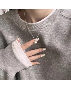 Close-up of minimalist sterling silver water drop pendant necklace on a knit sweater
