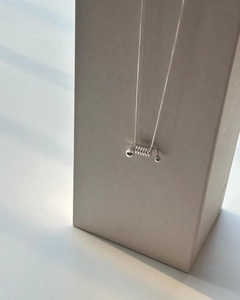 Macro detail of minimalist S925 sterling silver spring coil pendant on a sleek snake chain