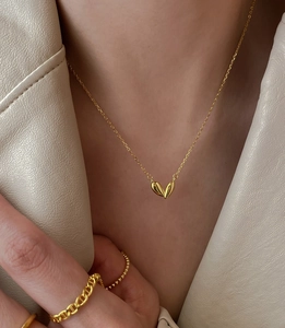 Detailed view of polished gold heart pendant necklace with elegant anchor chain ring