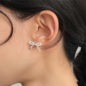 Macro side view of a model wearing elegant 925 sterling silver pearl bow stud earrings