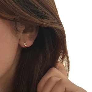 Boucles d'oreilles créoles dorées torsadées au design géométrique porté par un mannequin