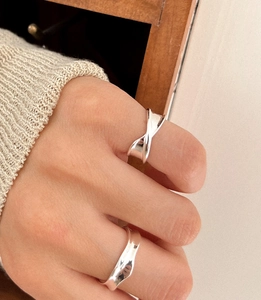 Detail view of stylish 925 silver wave and twisted rings on a female model hand