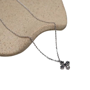 Minimalist 925 sterling silver necklace with black zircon clover pendant on beige ceramic