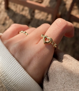 Detailed close-up of a gold-plated hollow heart ring worn on a finger for a stylish look