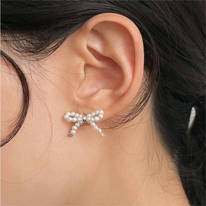 Elegant 925 sterling silver bow earrings with round white pearls on a model ear