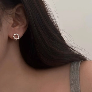 Macro view of minimalist beaded silver metal hoop earrings worn on female ear