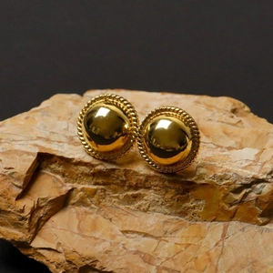 Vintage gold dome stud earrings with twisted rope edges on natural textured stone