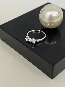 Dettaglio di un anello a fiocco d'argento con fascia regolabile su supporto nero