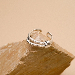 Minimalist S925 sterling silver double-layered knotted ring displayed on a natural rock