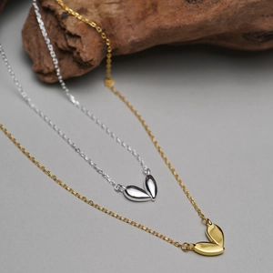 925 silver heart necklace in gold and silver leaf-shaped design on wooden block