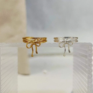 Elegant 925 sterling silver bow ribbon rings in gold and silver finish on textured glass